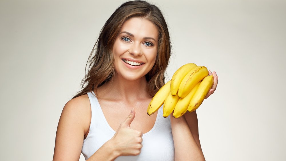 a woman with white teeth holding bananas