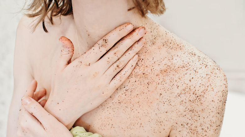 A woman applying body scrub on herself