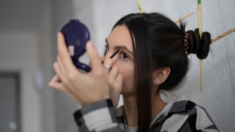 Woman applying eyebrow pencil