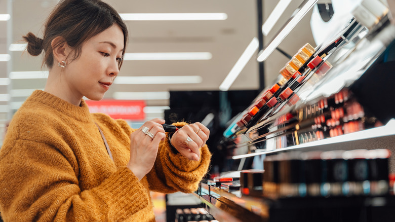 Woman testing lipstick color on hand at makeup store