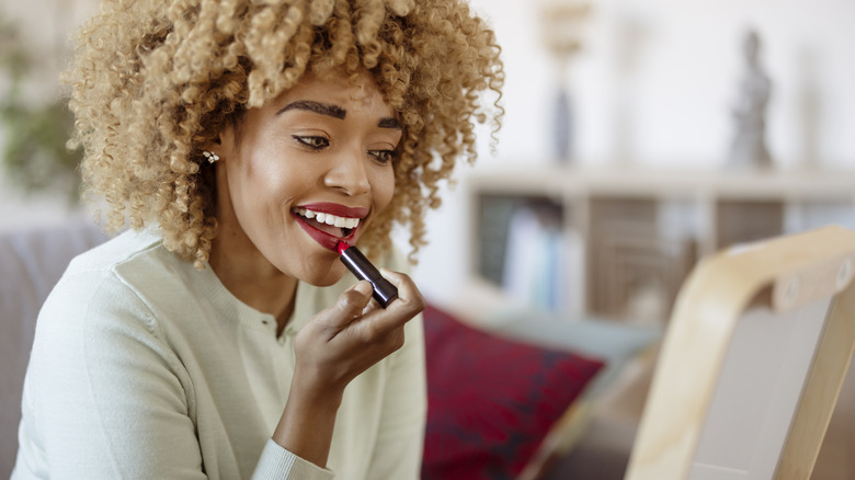 Woman applying lipstick in mirror