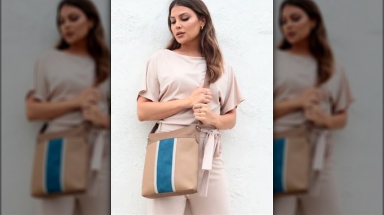 Model carrying a brown tote with teal stripe