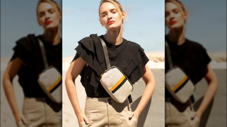 Model wearing a black and yellow race-stripe sling bag