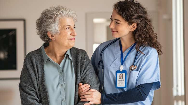 Elderly woman walking with nurse