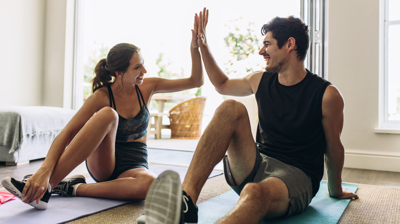 Man and woman high-fiving on workout mats