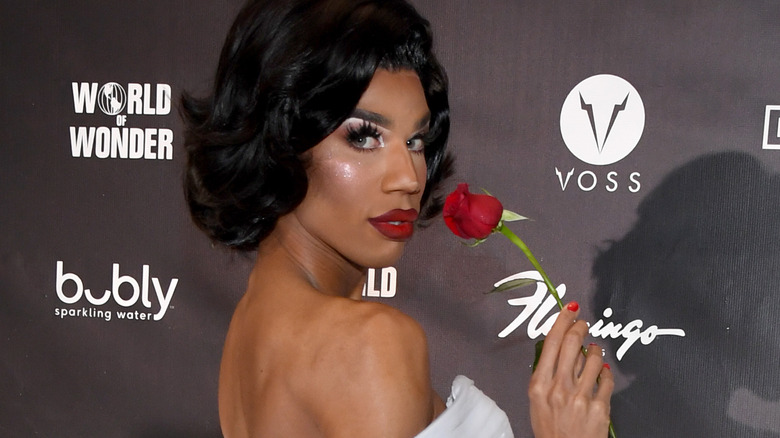 Naomi Smalls in white holding a rose 