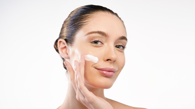 A woman applying lotion to her face 