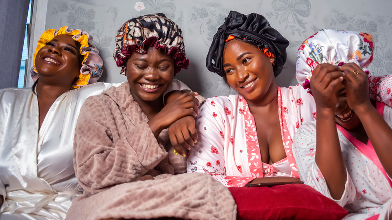 Group of friends laughing wearing hair bonnets