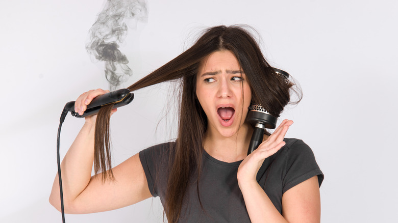 woman burning hair with flat iron