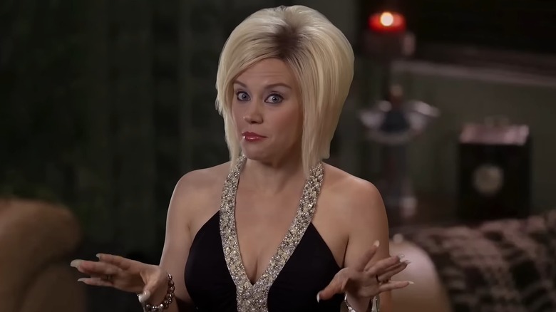 Kate McKinnon with big hair and long nails as The Long Island Medium