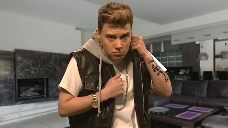 Kate McKinnon as Justin Bieber, pulling leather vest up to neck "seductively"