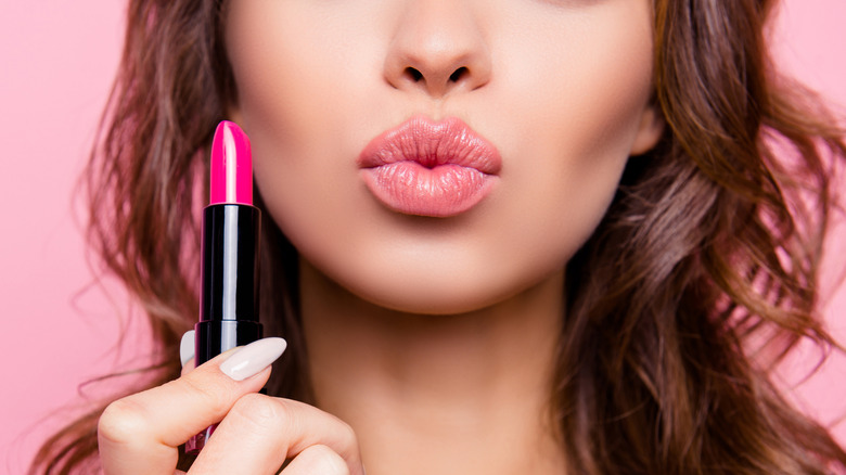 Woman holding fucshia lipstick