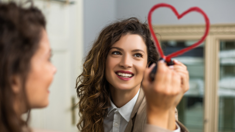 Woman uses lipstick on mirror