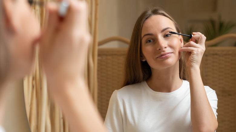 Woman applying mascara in mirror