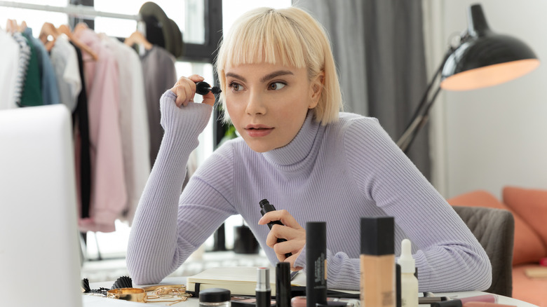 blonde woman putting mascara on