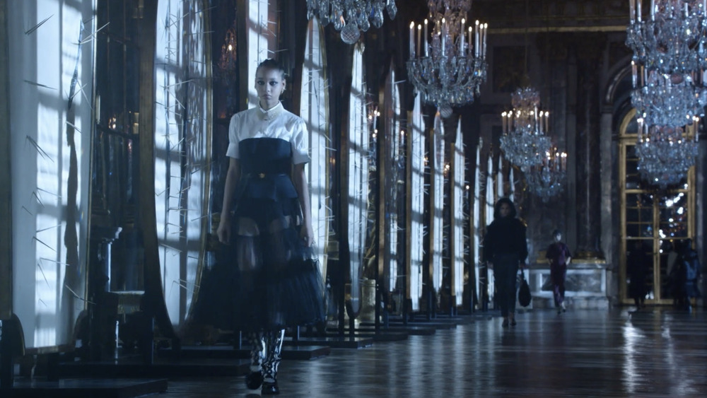 Models walking for Dior under chandeliers