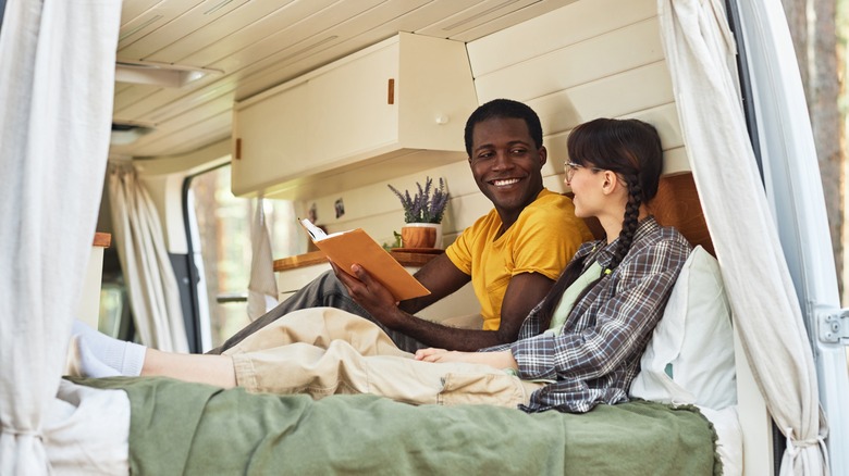 Interracial couple reading together in travel camper