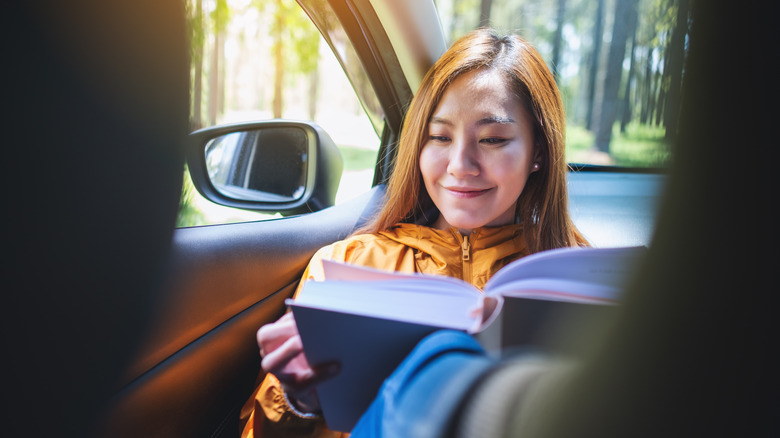 Asian woman reading in a car