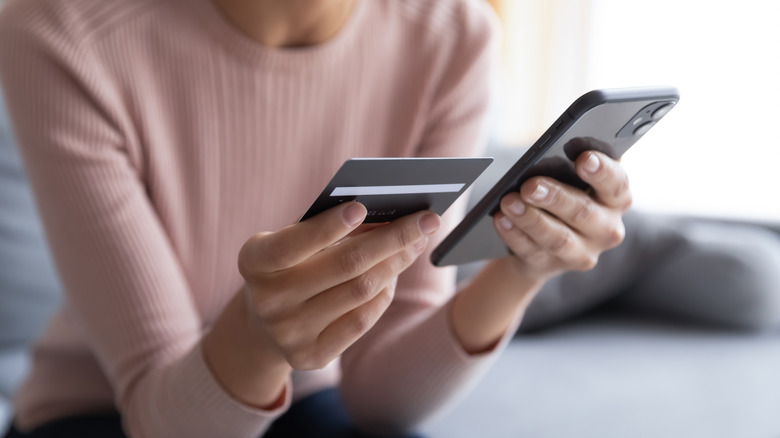 Woman holds her phone and credit card