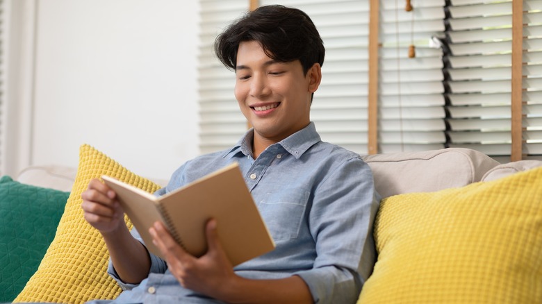 man reading book on couch 