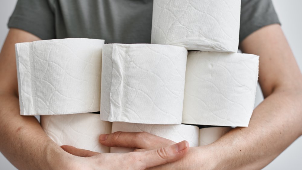 man holding rolls of toilet paper