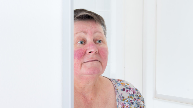 Older woman with rosacea looking at herself in the mirror