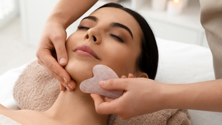 Woman using gua sha during facial treatment