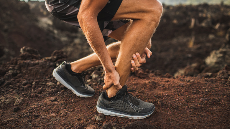 Man gripping heel on trail