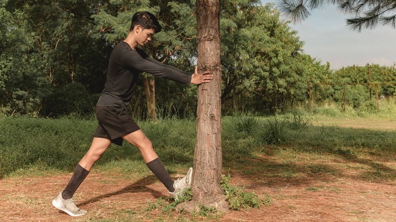 Man stretching against tree