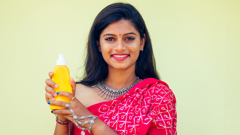 Woman wearing sari and carrying bottle of sunscreen