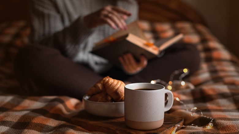 woman sitting cross-legged on a bed reading a book 