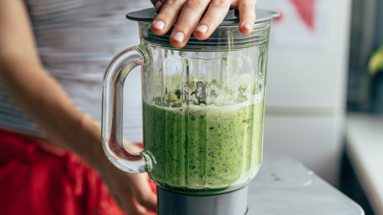 Woman blending a green smoothie
