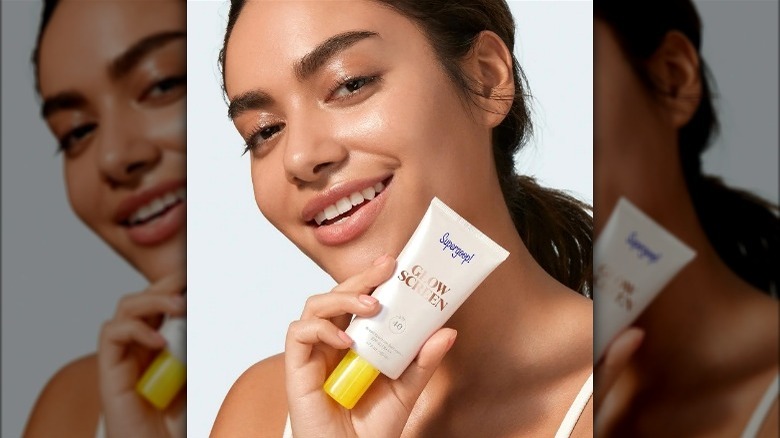 Model holding tube of tinted spf moisturizer