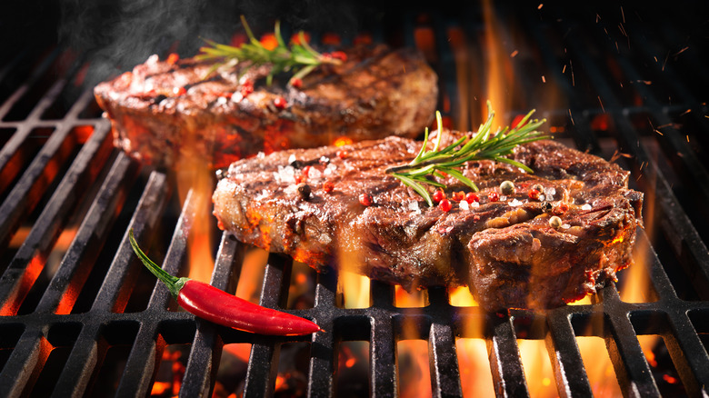 Steak cooking on a grill with flames