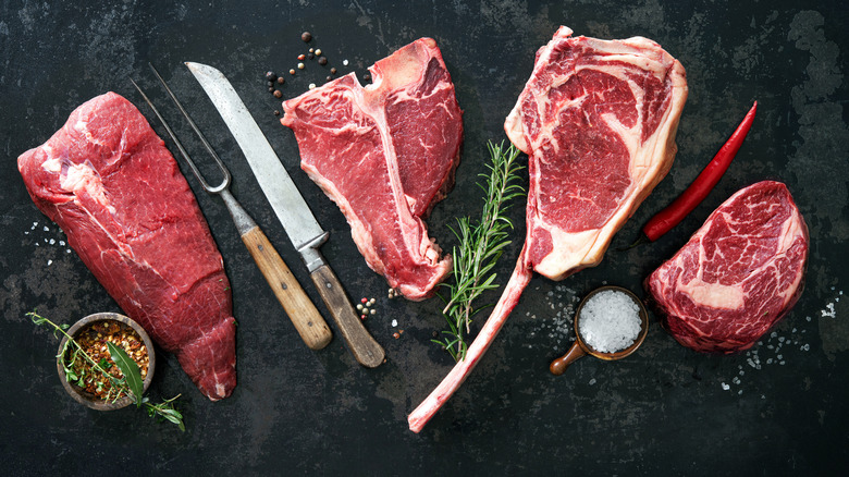 Raw steaks with herbs and cutlery