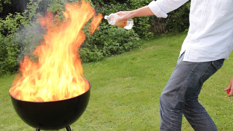 A person putting lighter fluid on fire