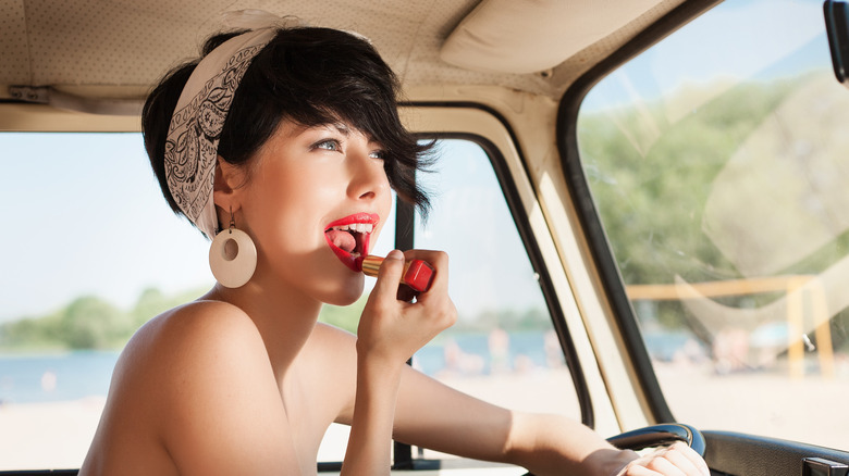 woman applying lipstick in car