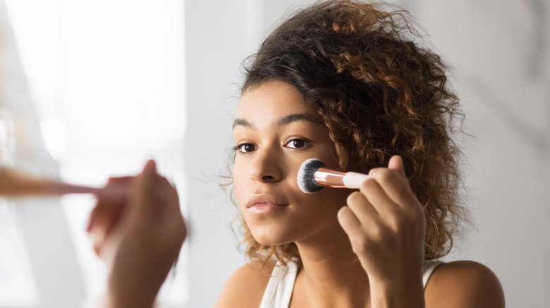 woman applying makeup with brush