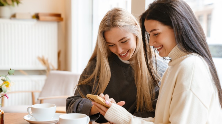 two women smiling at smartphone