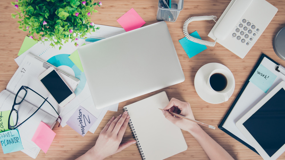 Person making list surrounded by office equipment