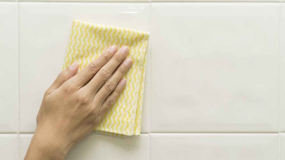woman cleaning a tiled wall