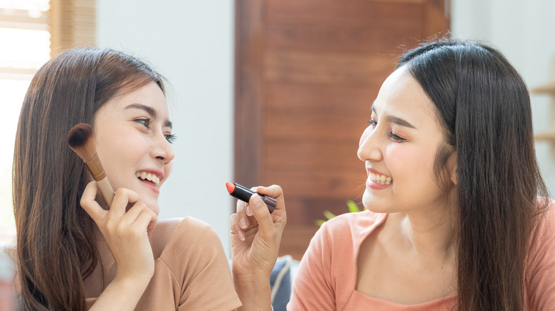 women sharing makeup 