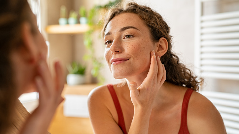 Woman looking in the mirror at her skin