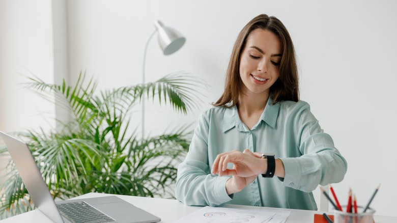 Woman in blue looks at smartwatch