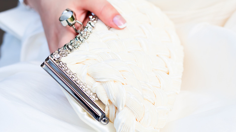 hand holding off-white clutch bag