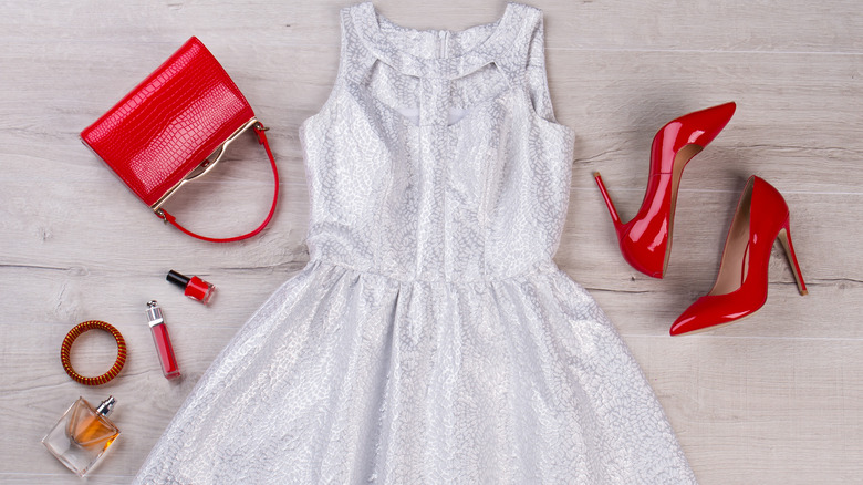 white, silvery dress surrounded by red accessories