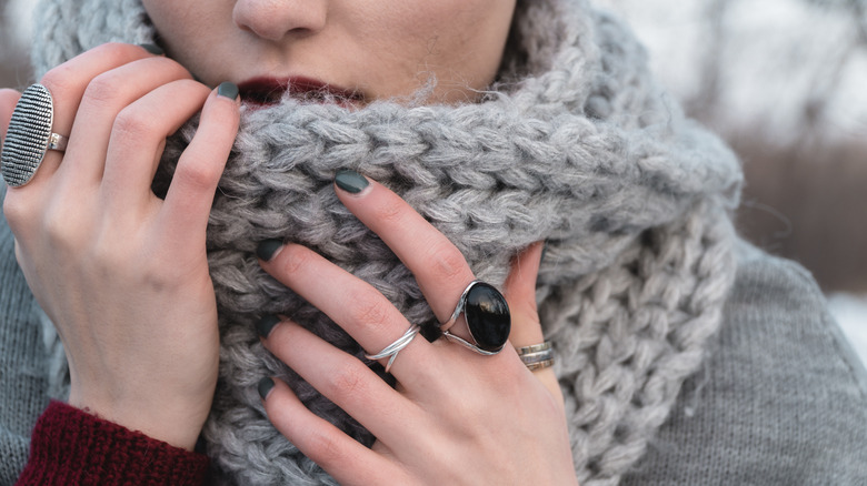 woman's hands holding onto chunky scarf she's wearing