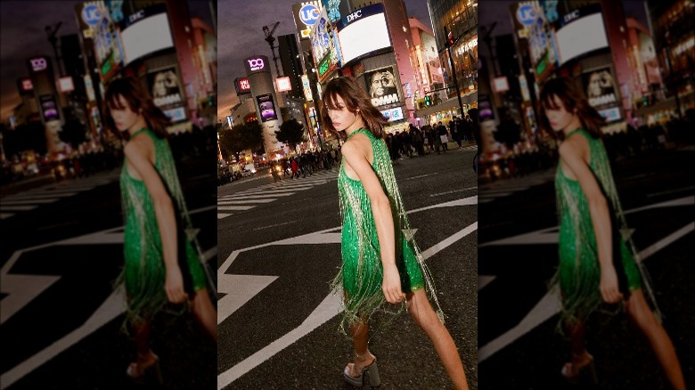 Nasty Gal model wears mini green fringe dress on city street