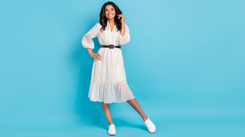 Woman posing in white dress with sneakers