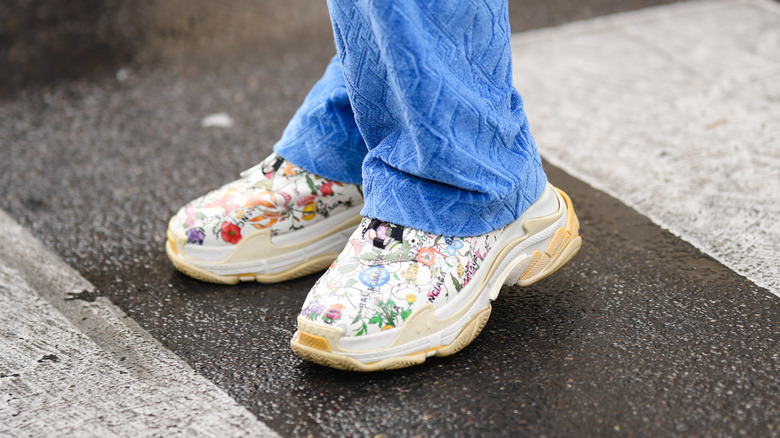 Person wearing printed chunky sneakers with blue pant